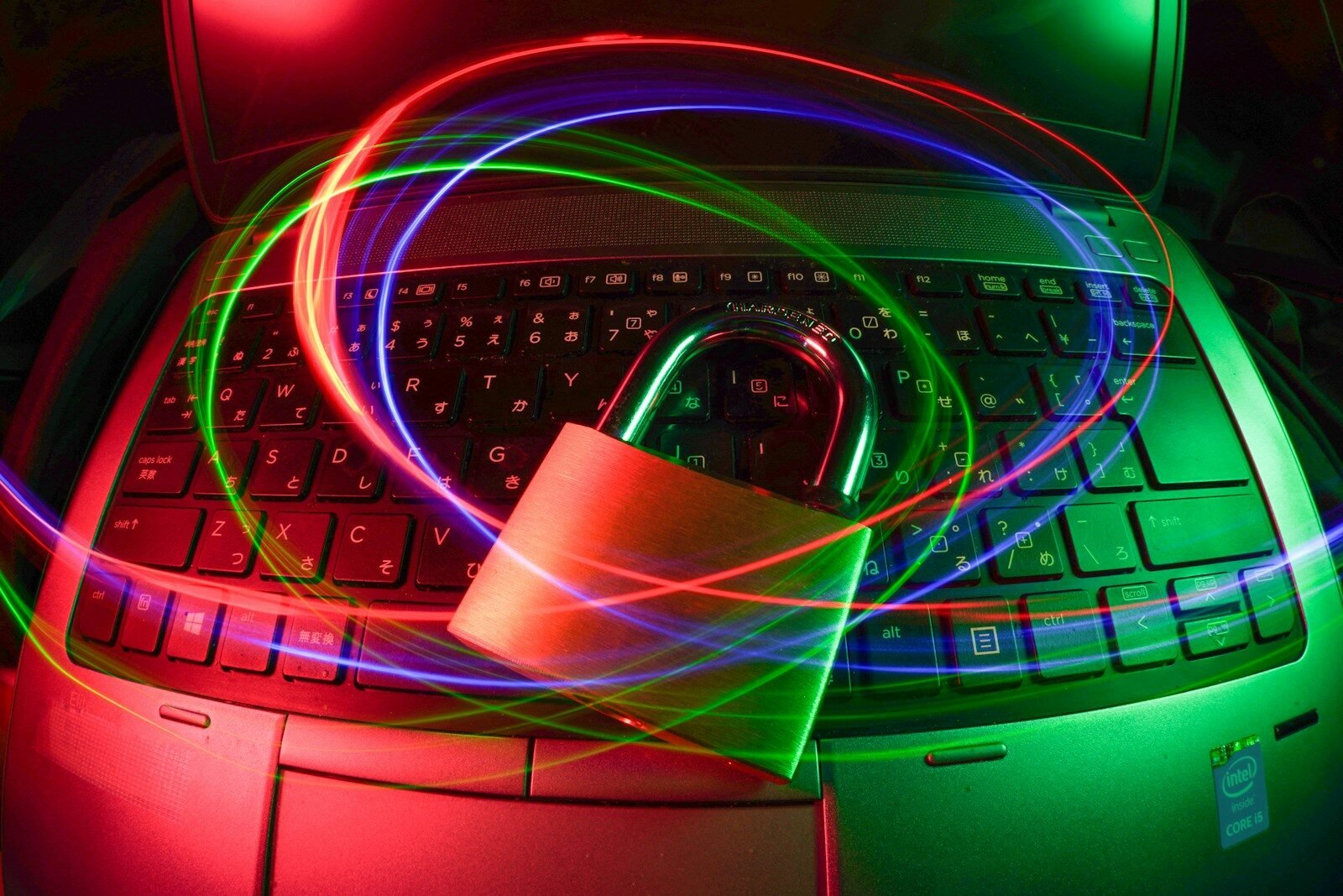 Padlock on a laptop keyboard surrounded by glowing light trails, illustrating passwords and two-factor authentication for securing online accounts
