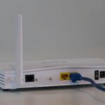 White Wi-Fi router with cables connected on a white table, illustrating a home Wi-Fi network setup guide