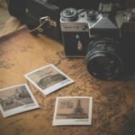 DSLR camera beside scattered printed photographs on a vintage map, illustrating how to organize a digital photo library