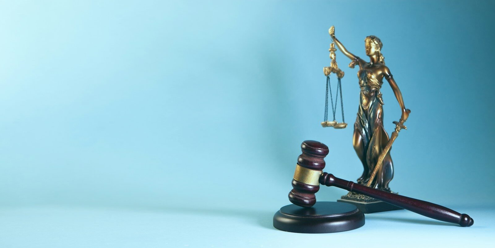 Lady justice statue and gavel on a blue background, illustrating AI regulation around the world