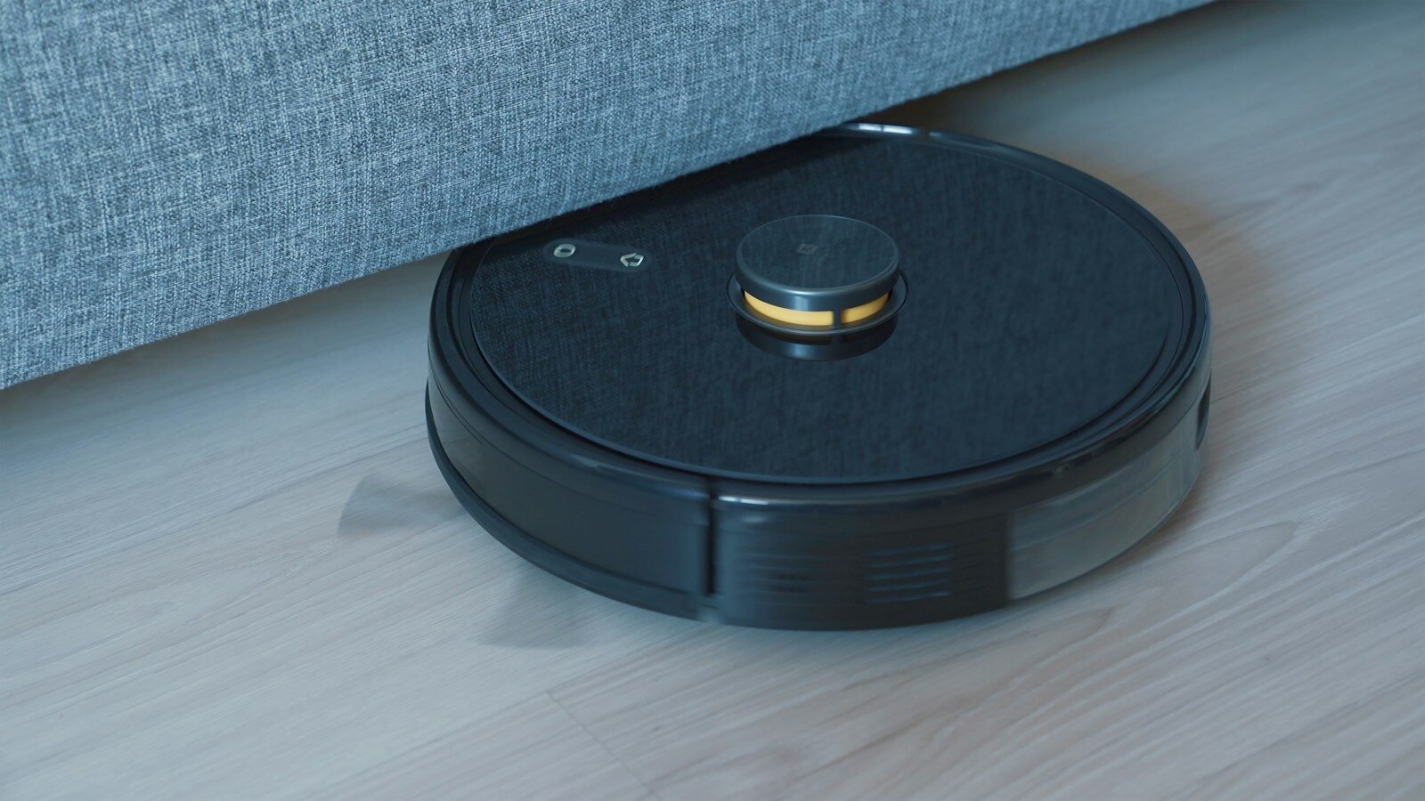 Black robot vacuum cleaner on a wooden floor, illustrating a robot vacuum buying comparison guide