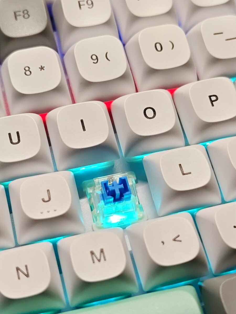 Close-up of a white mechanical keyboard with blue switches and white keycaps, illustrating a beginner guide to mechanical keyboards